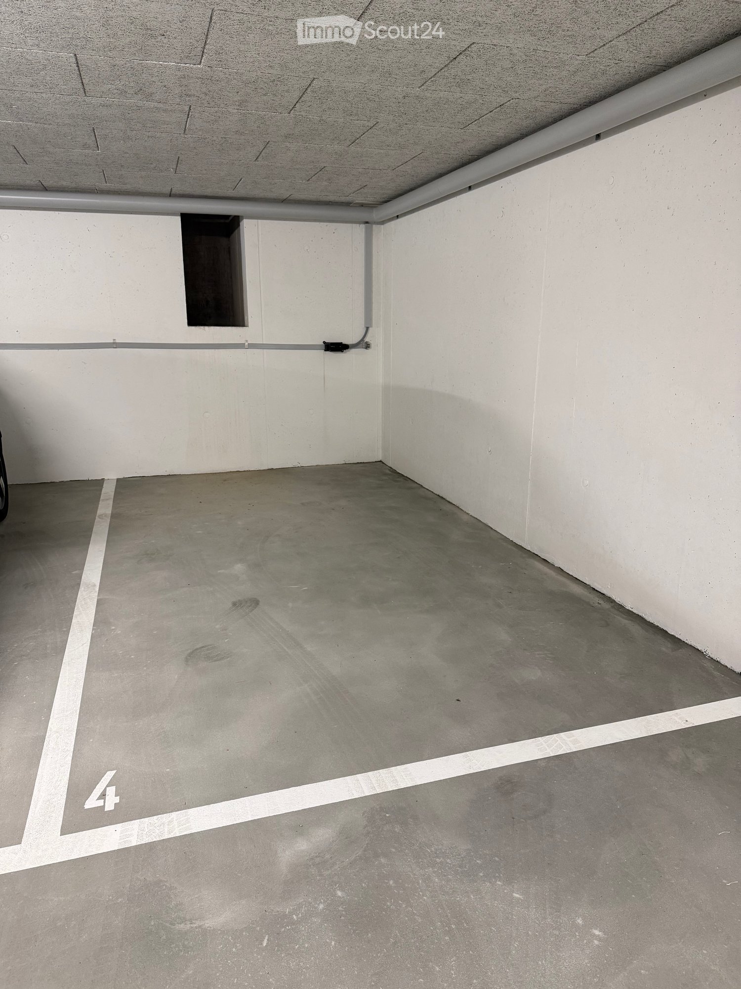 Empty underground parking space with concrete floor and white walls, marked with number '4'.