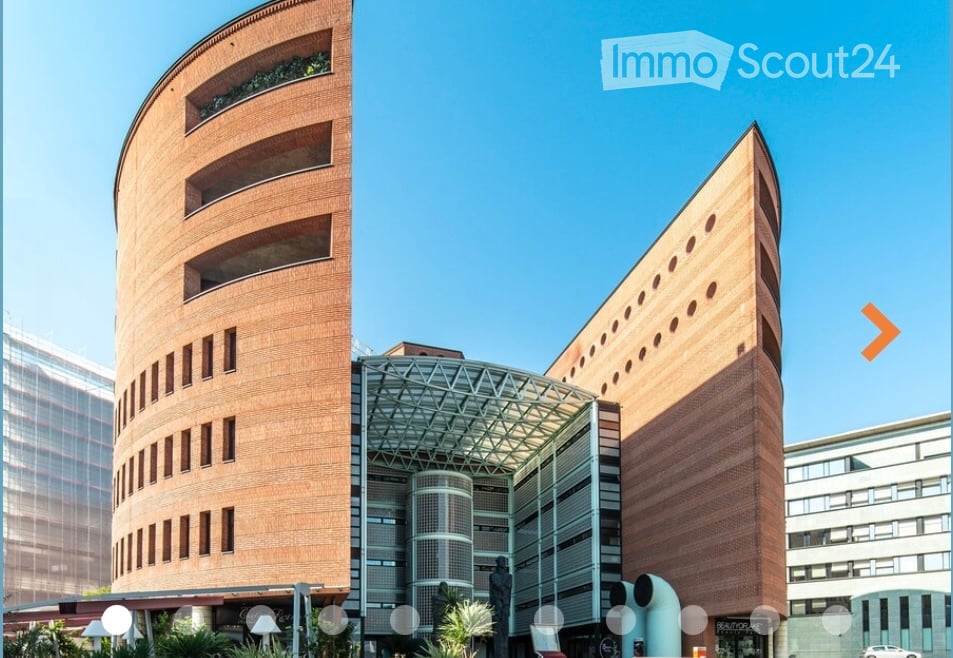 Modern building with curved brick facades, glass entrance, and geometric design.