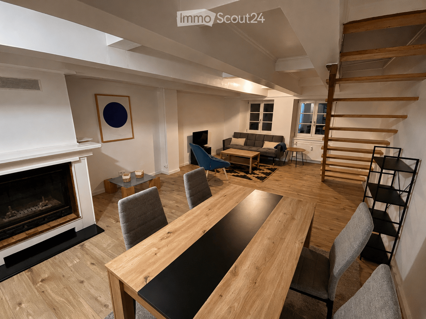 Modern living and dining area with wooden floors, fireplace, sofa, coffee table, dining table, and chairs.