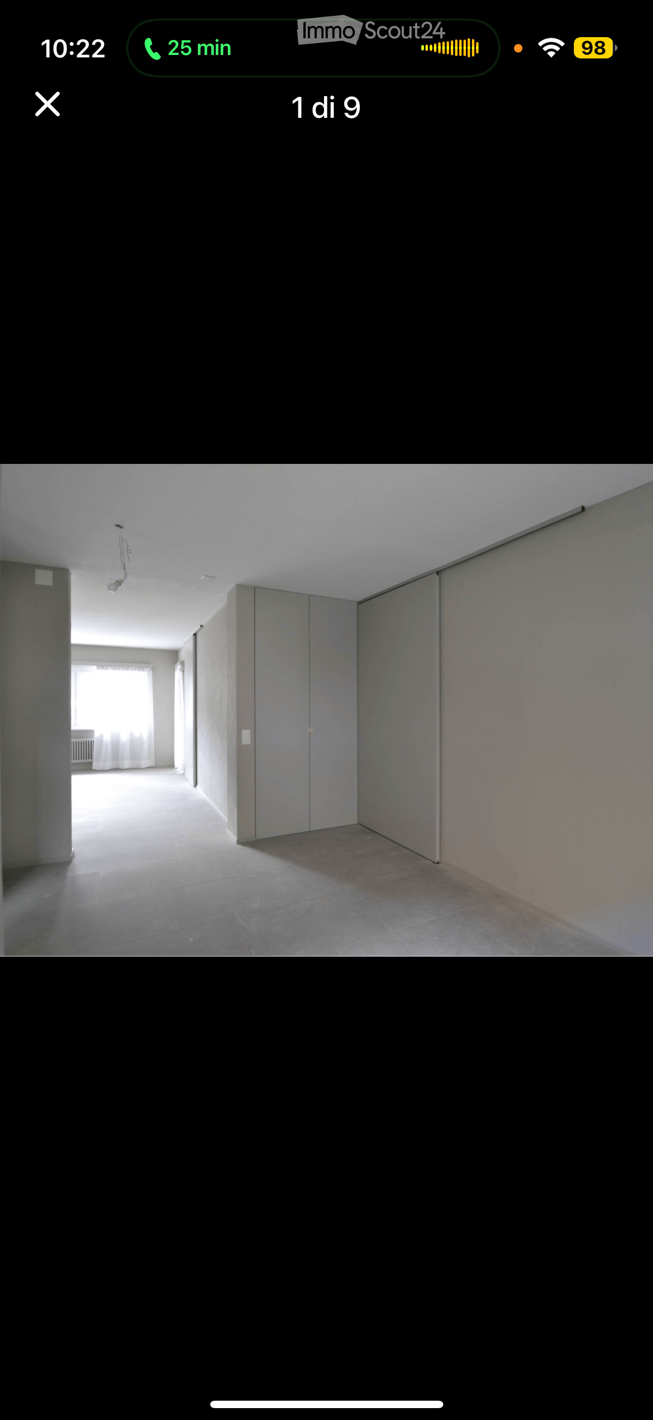 Empty room with tiled floor, grey walls, and a window with white curtains in the background.