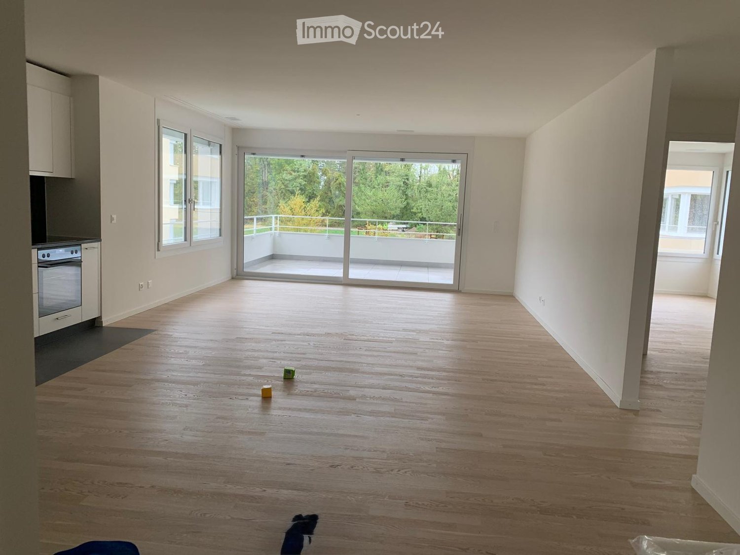 Empty room with wooden flooring, white walls, and large sliding glass doors leading to a balcony.