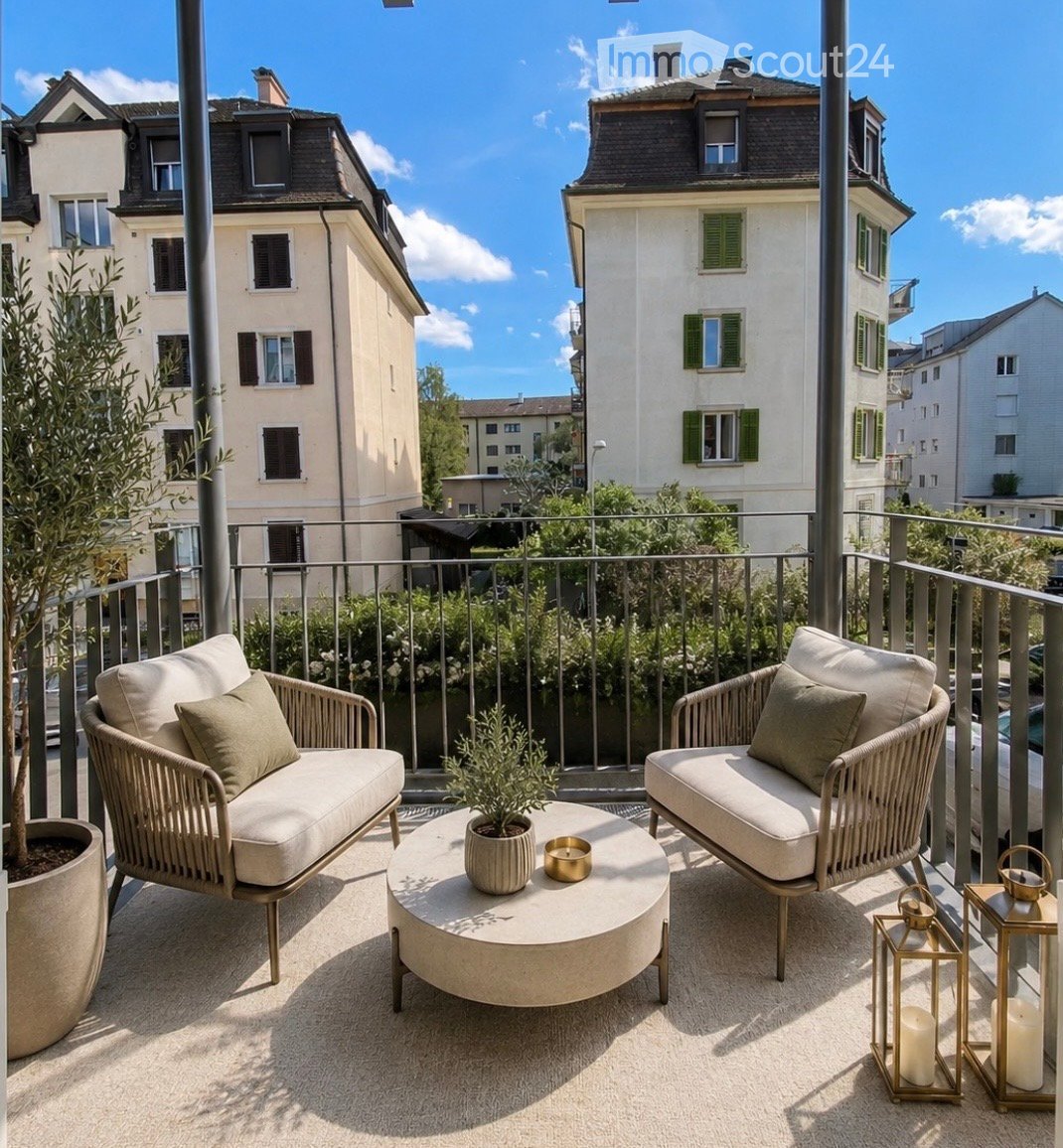 A modern balcony with two wicker sofas, a round coffee table, potted plants, and lanterns, overlooking a cityscape with classic buildings.