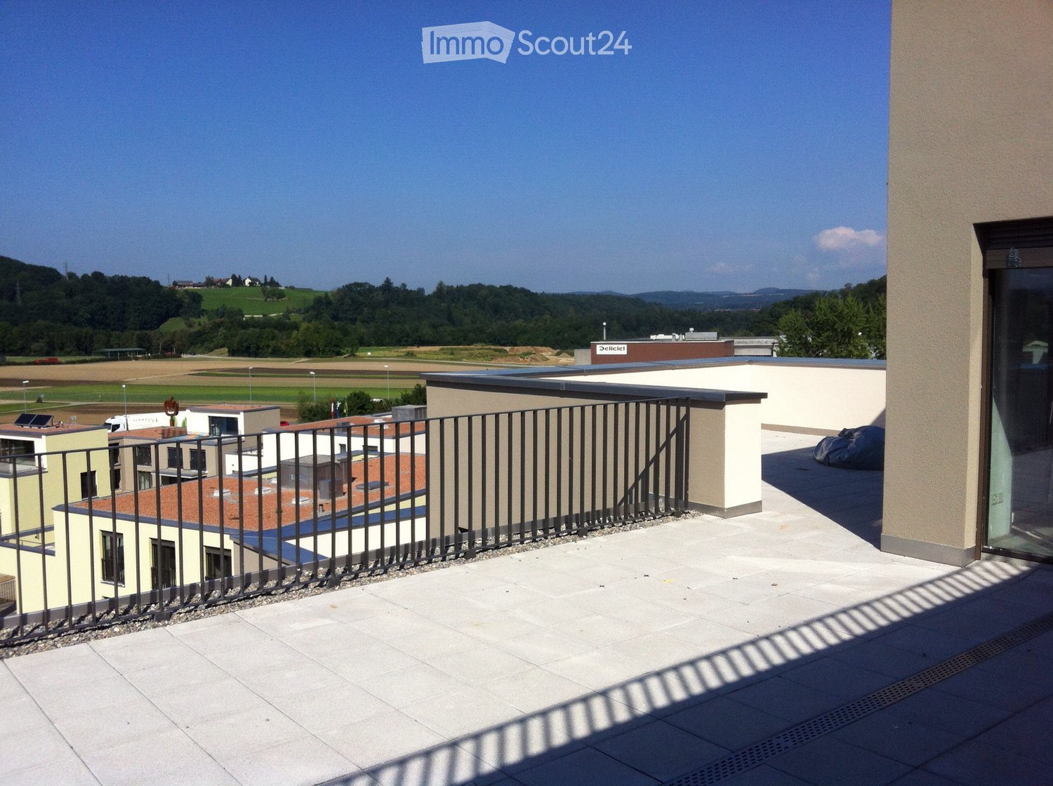 Roof terrace with tiled flooring, metal railing, and scenic countryside view.