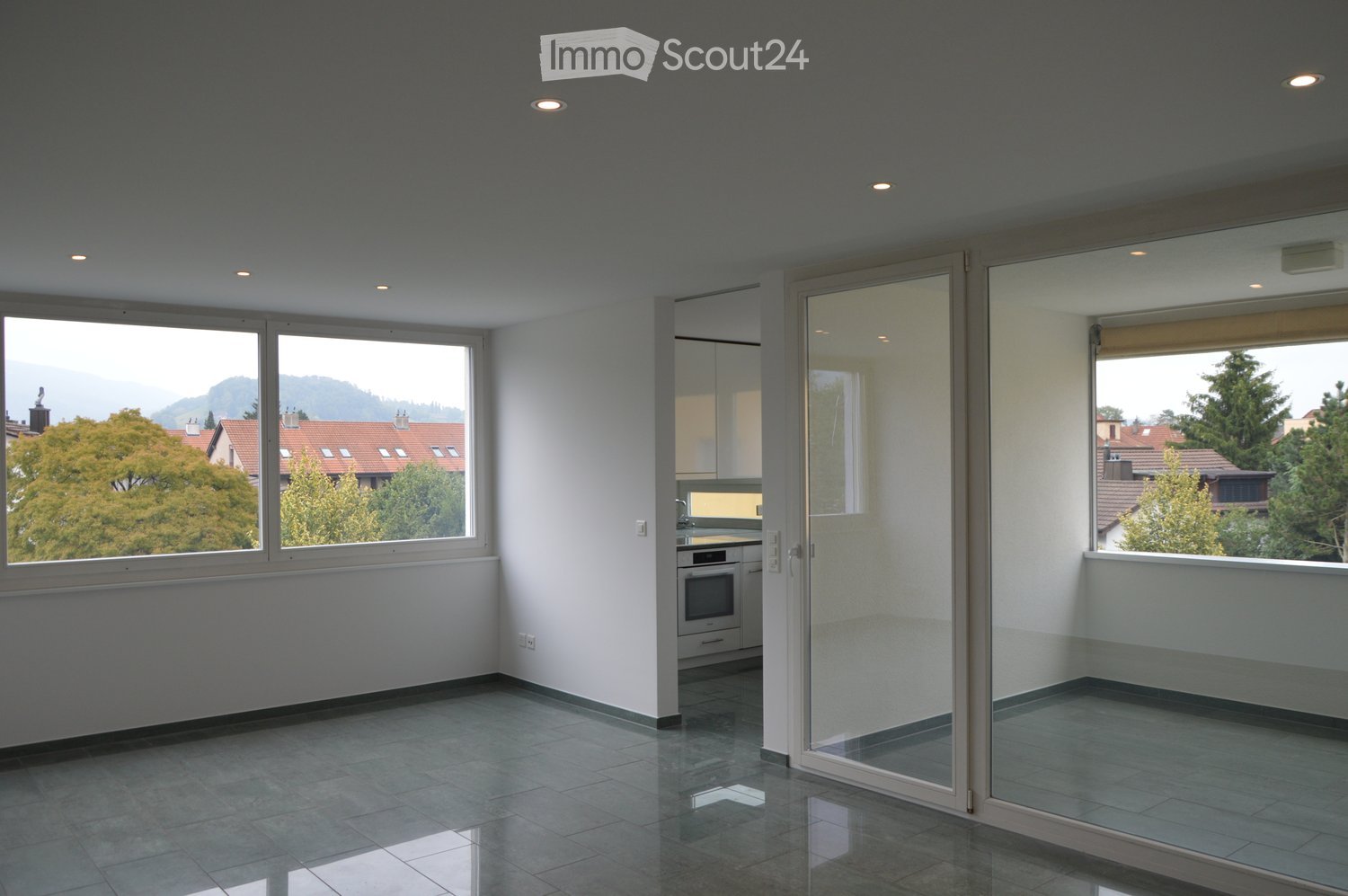 Empty room with large windows, tiled floor, and modern ceiling lights. No furniture or equipment present.