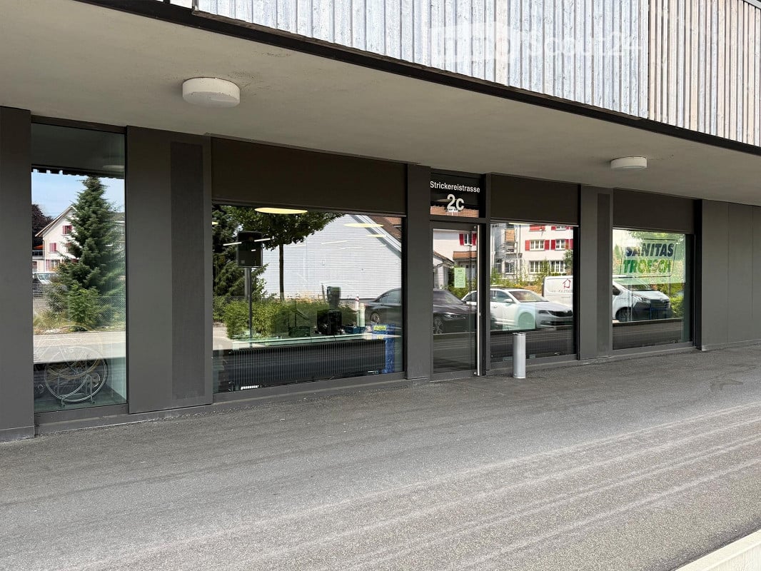 Modern commercial building entrance with large glass windows and doors, labeled "2c" and "Stricklerstrasse".