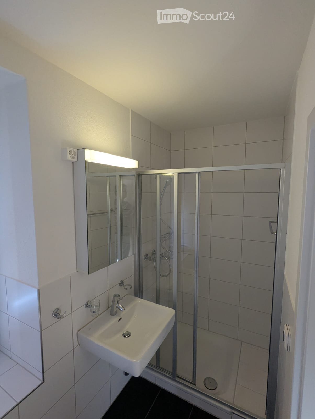Modern bathroom with a white sink, mirror with built-in lighting, and a glass-enclosed shower area.