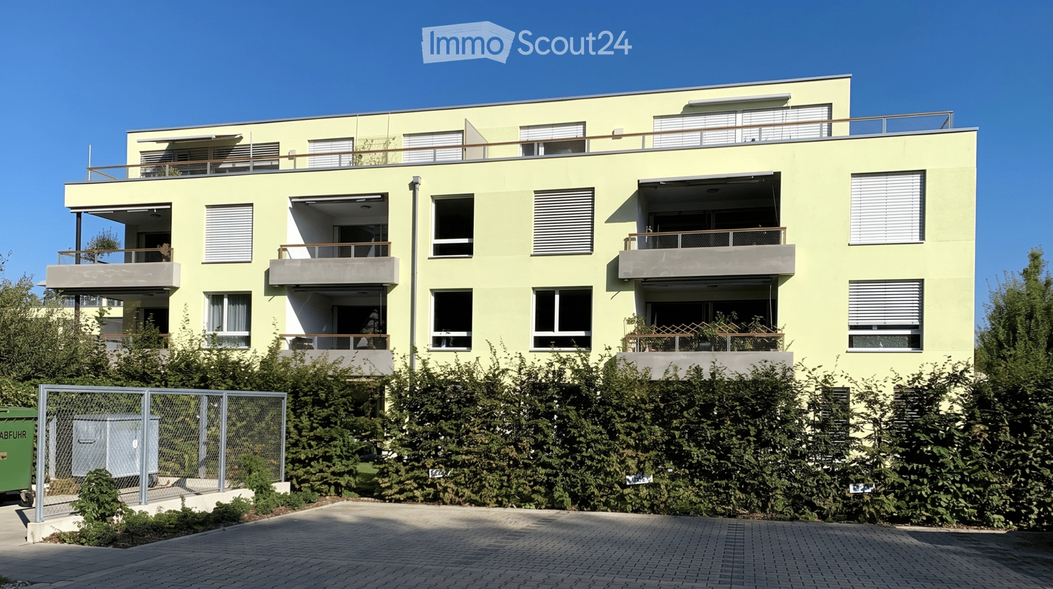 Modern three-story residential building with light yellow facade, multiple balconies, and large windows.