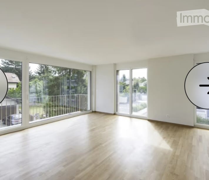 Bright, empty room with large windows and wooden flooring, featuring a sliding glass door leading to a balcony.