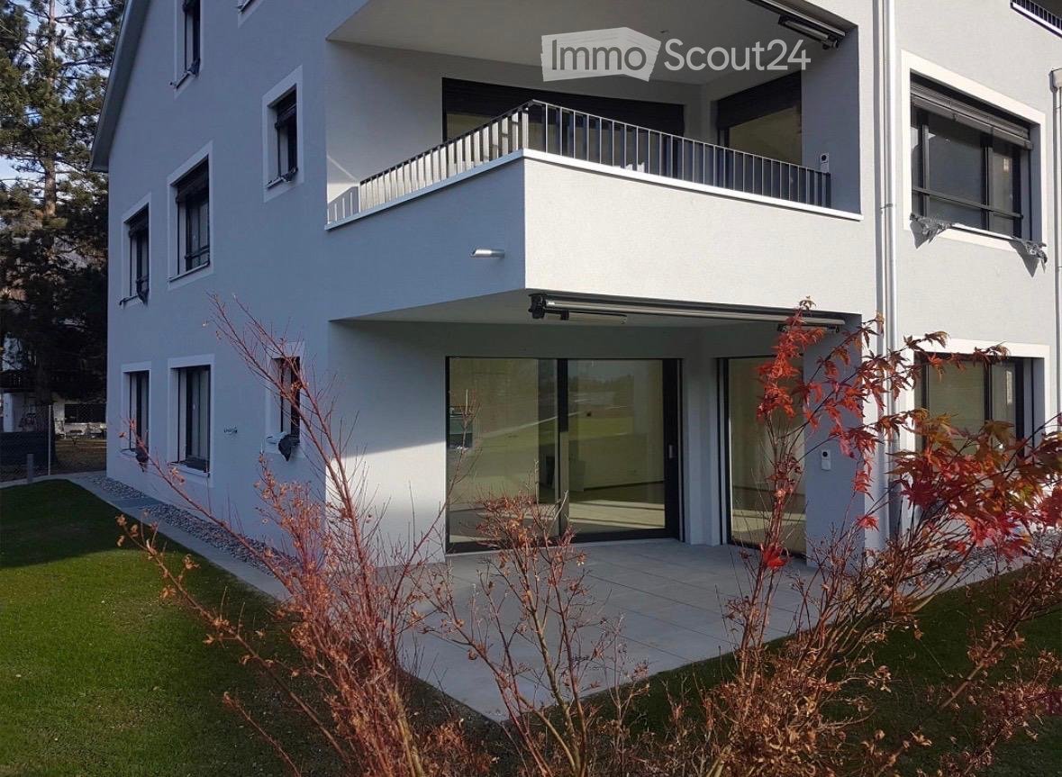 Modern two-story house with white exterior, large windows, and a balcony on the upper level.