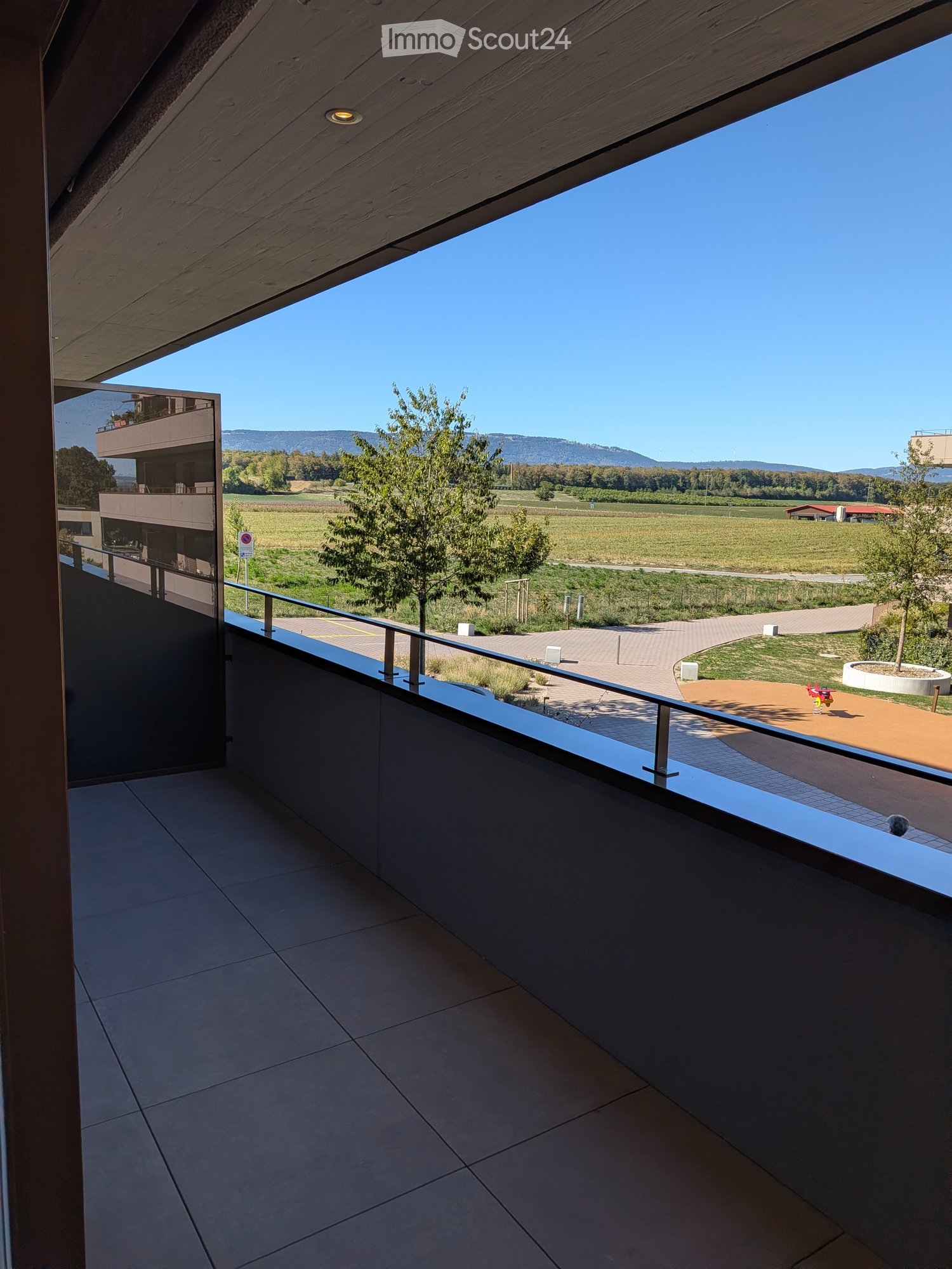 Balcony with tiled floor, metal railing, and scenic view of countryside and mountains.