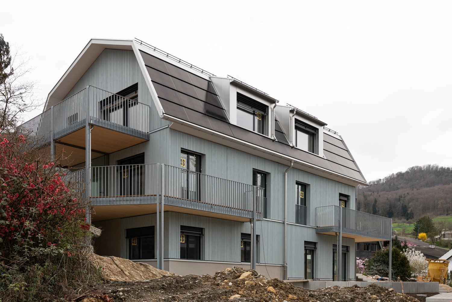 3 story house, gray exterior, multiple balconies, modern design, under construction