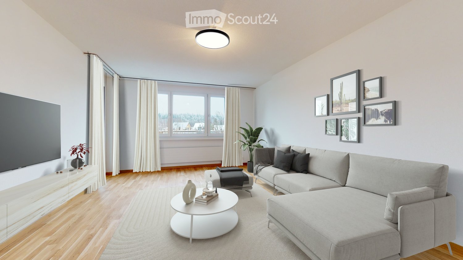 Modern living room with light grey sofa, white coffee table, ottoman, and large windows with white curtains. Features a television on a white stand, a plant, and several picture frames on the wall.