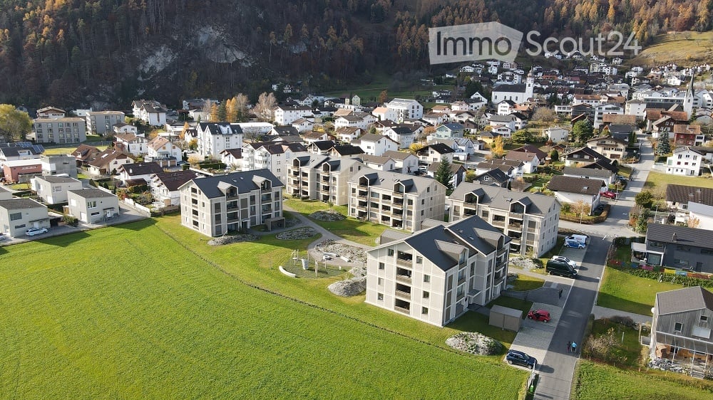 Aerial view of a residential area with multiple apartment buildings, houses, and green spaces.