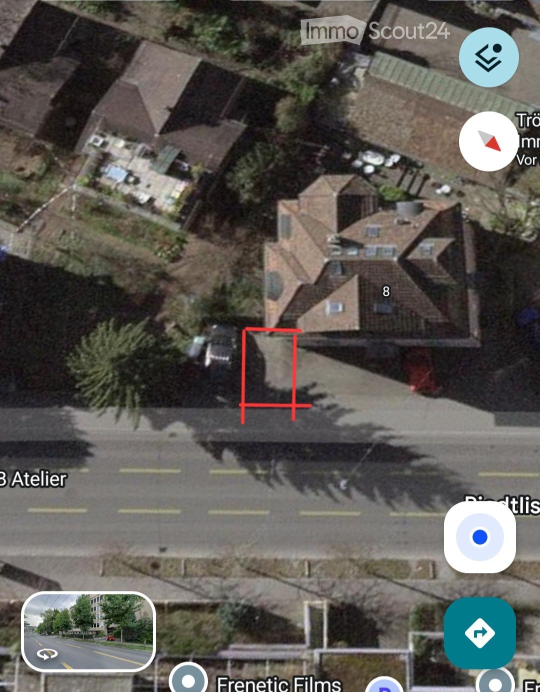 Aerial view of a residential area showing multiple houses with pitched roofs, surrounded by trees and a road.