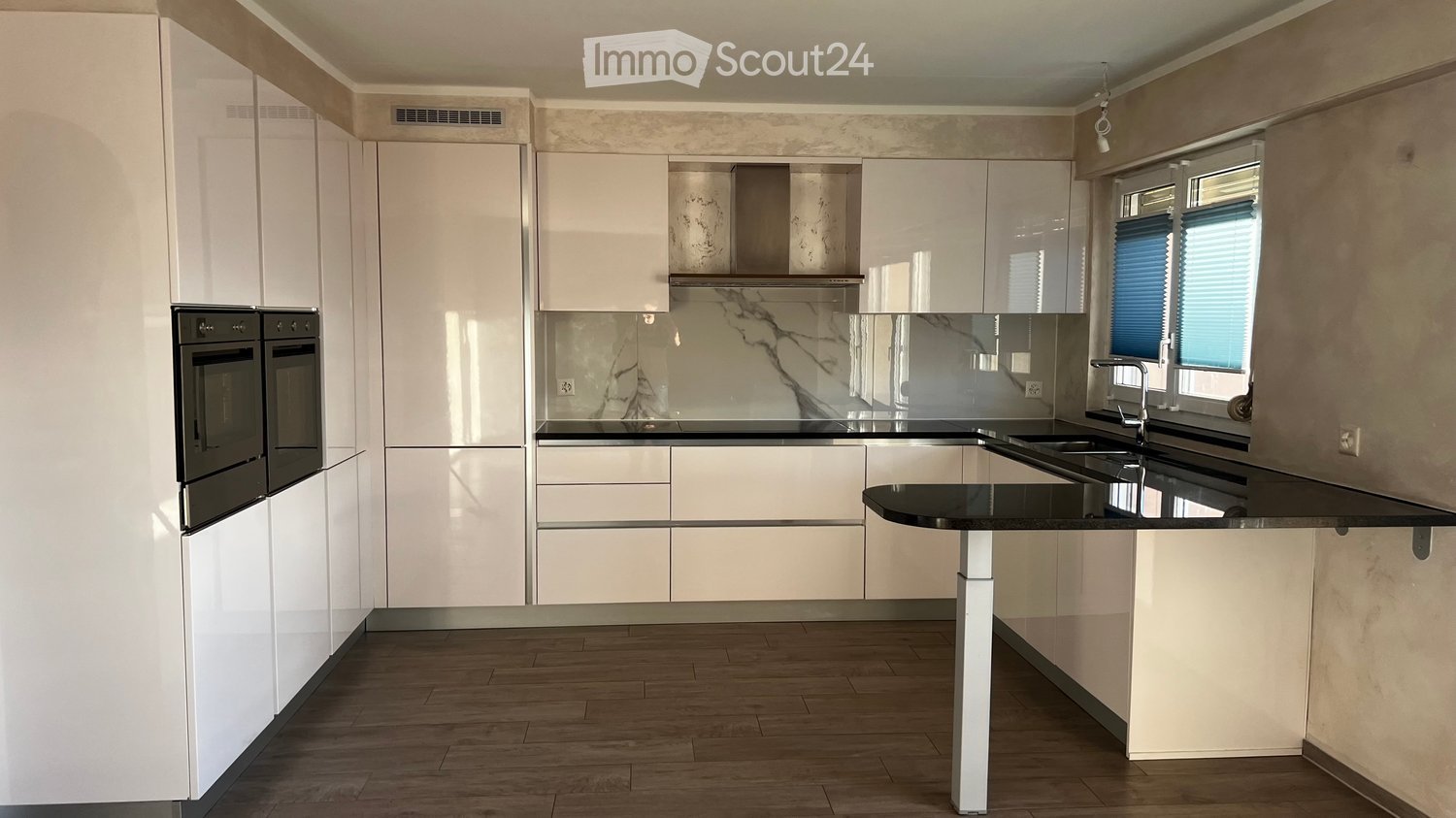 Modern kitchen with white cabinets, black countertops, stainless steel appliances, and a central island.