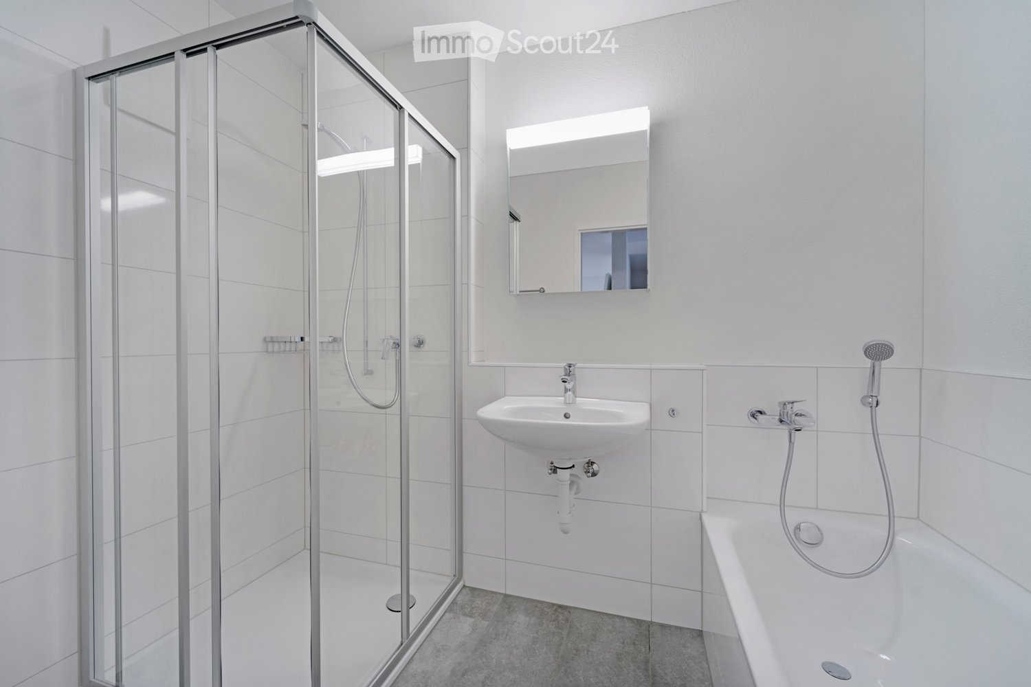 Modern bathroom with white tiles, a bathtub, a sink, a mirror, and a glass-enclosed shower stall.
