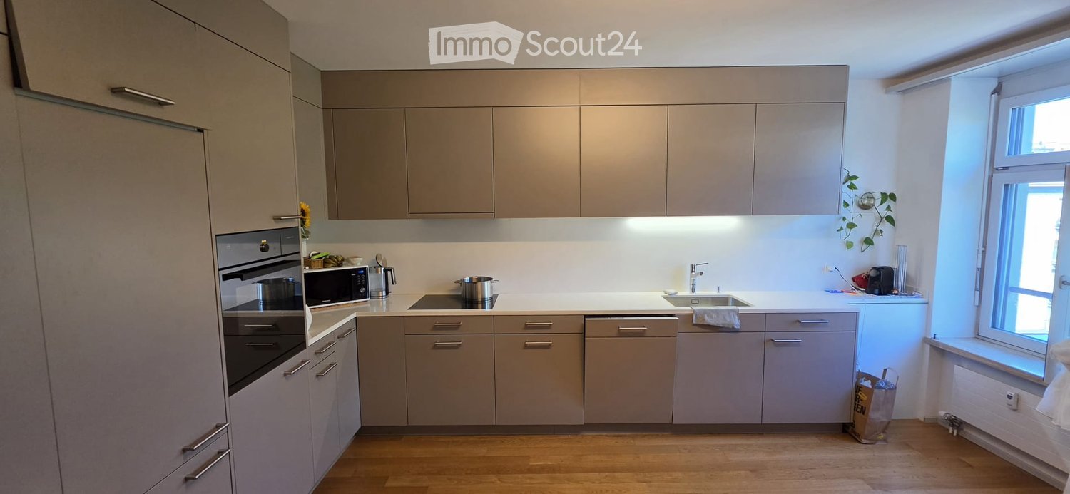Modern kitchen with light-colored cabinets, stainless steel appliances, and a large window letting in natural light.