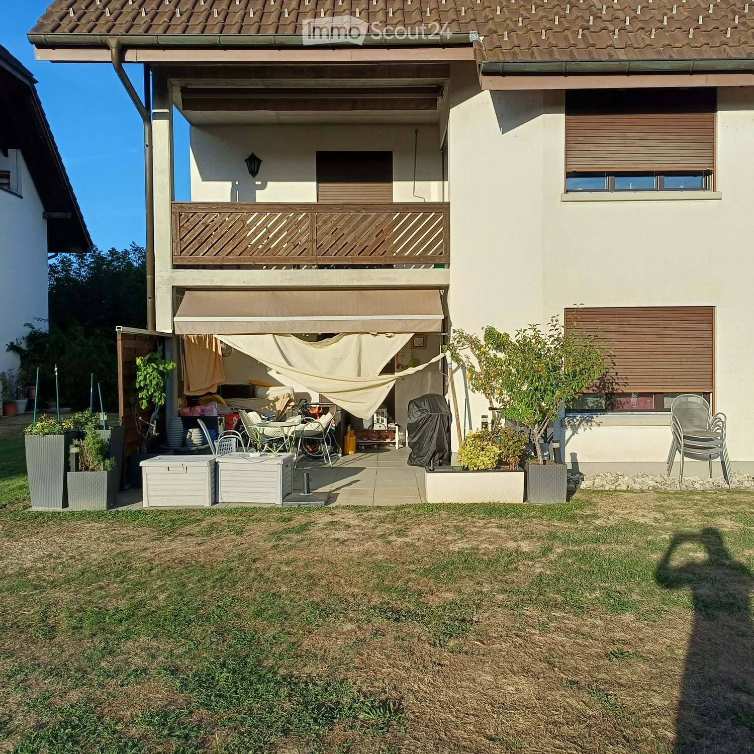 Garden area with a covered patio, outdoor furniture, plants, and storage boxes.
