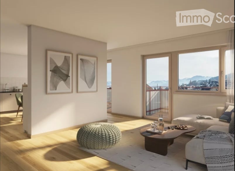 Bright, modern living room with large windows offering a scenic view, featuring a sofa, coffee table, ottoman, round stool, and framed artwork on the wall.