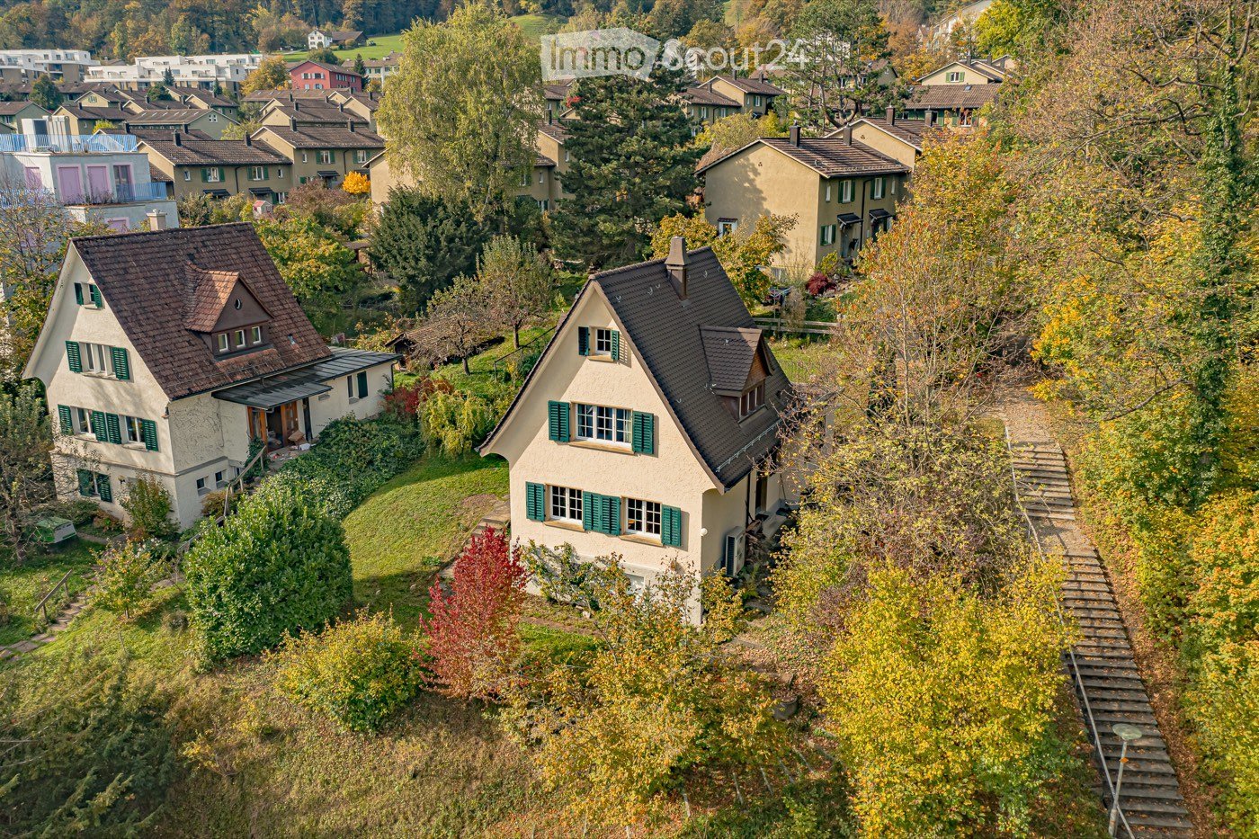 Aerial view of a residential neighborhood with multiple houses, surrounded by trees and greenery.