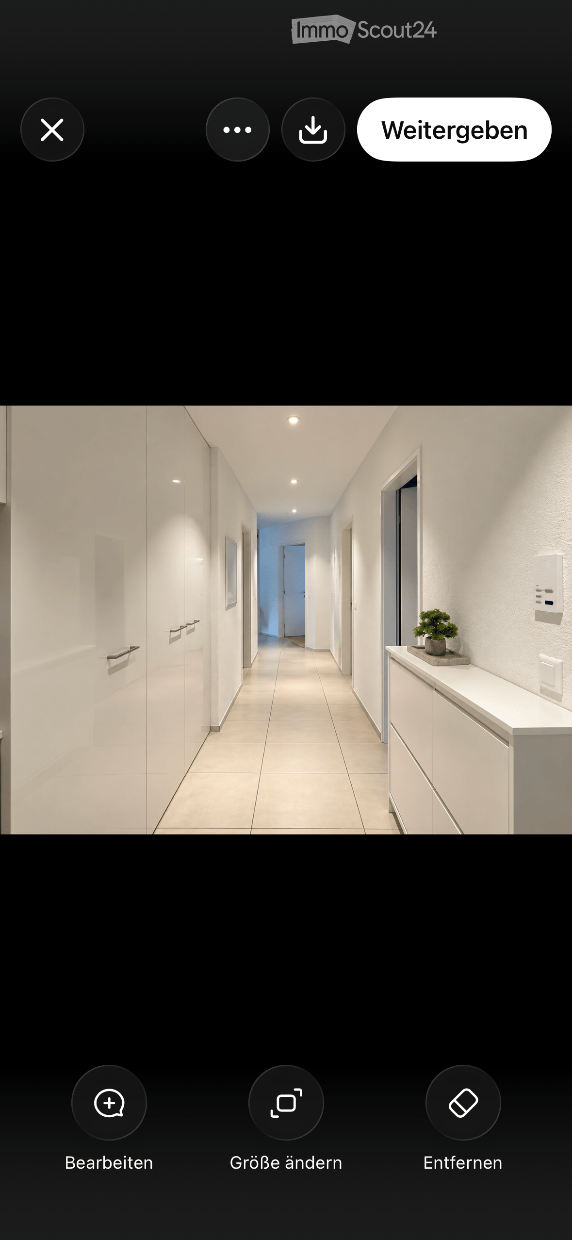Modern hallway with white walls, tiled floor, recessed lighting, and a small plant on a cabinet.