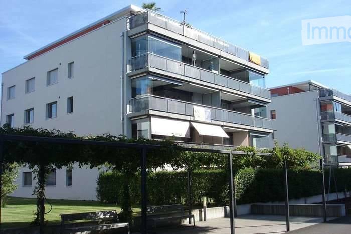 Modern multi-story building with large glass balconies and white facade.