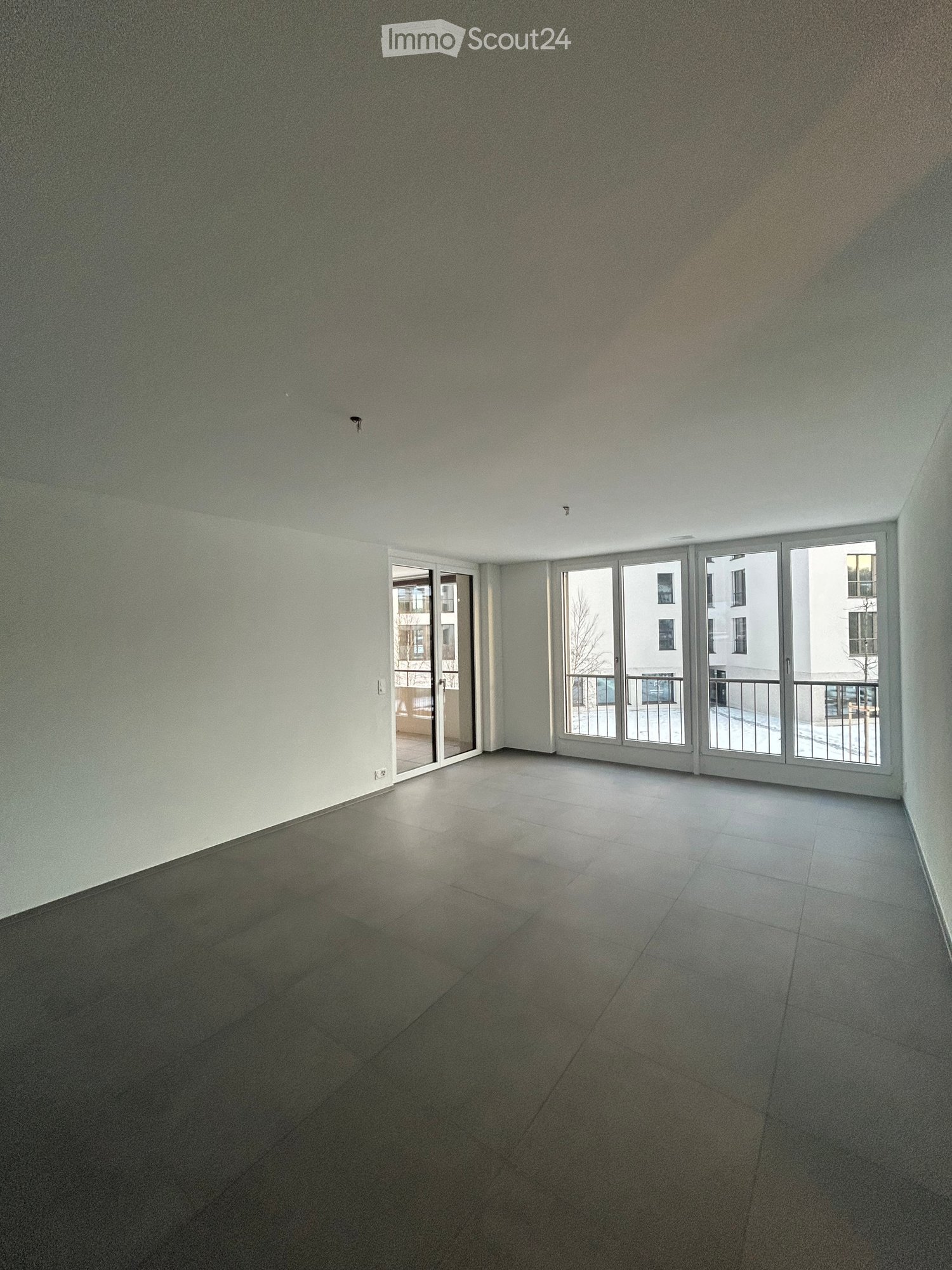 Empty room with tiled floor and large sliding glass doors leading to a balcony area.