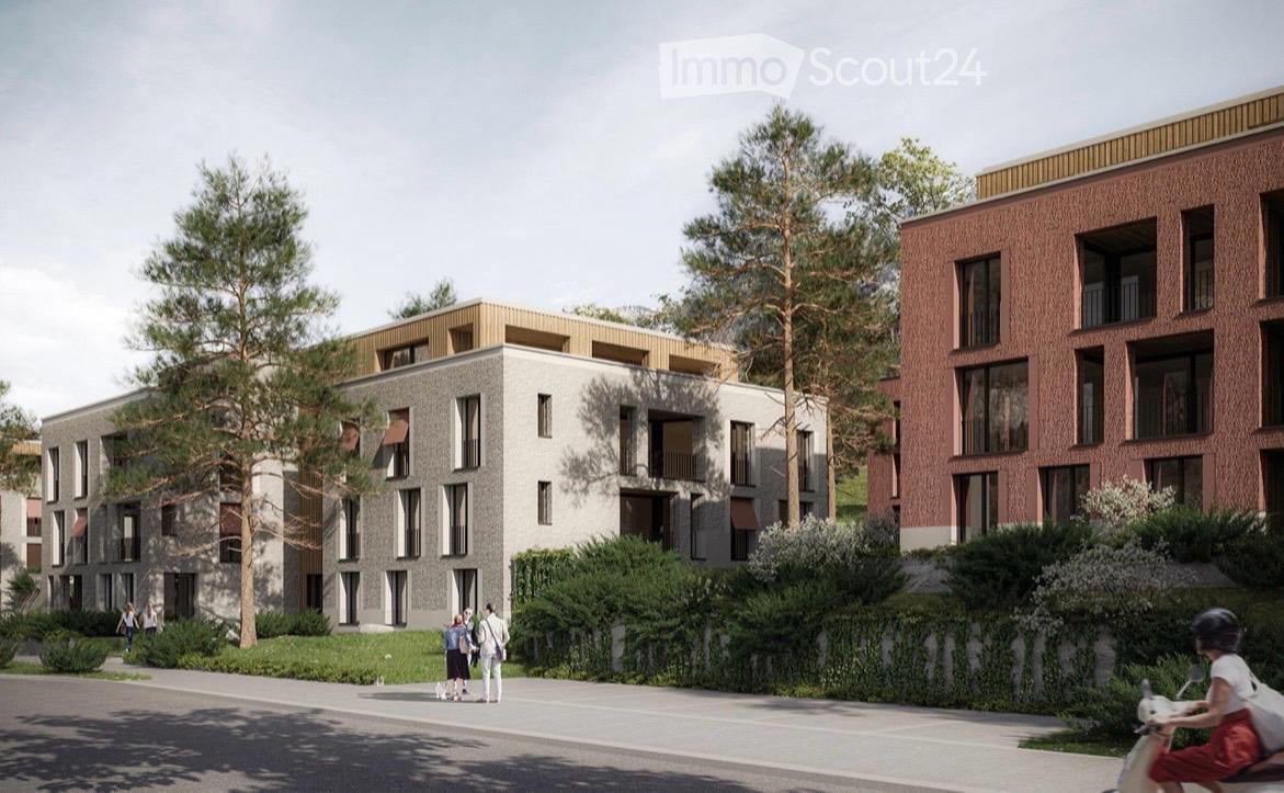 Modern multi-story residential building with contemporary design, featuring large windows, balconies, and a mix of grey and red brick facades.