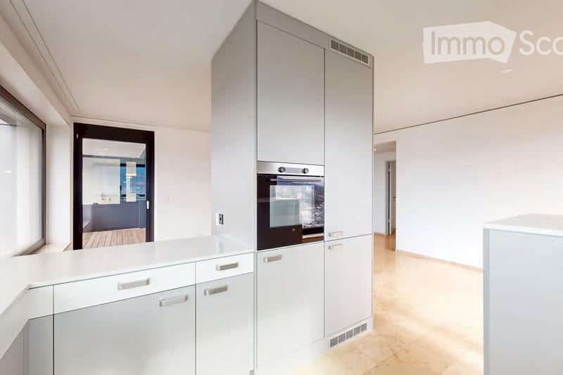 Modern kitchen with white cabinets, a built-in oven, and a light wooden floor.