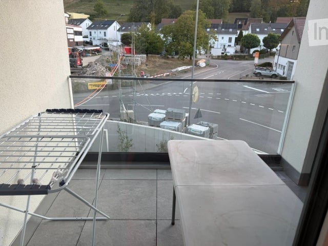 Balcony with laundry rack, overlooking a street with houses and construction area.