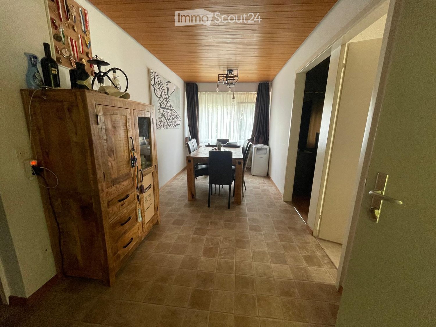 Hallway with tiled floor, wooden cabinet on left, dining area visible through an open doorway, and air conditioner unit in the background.