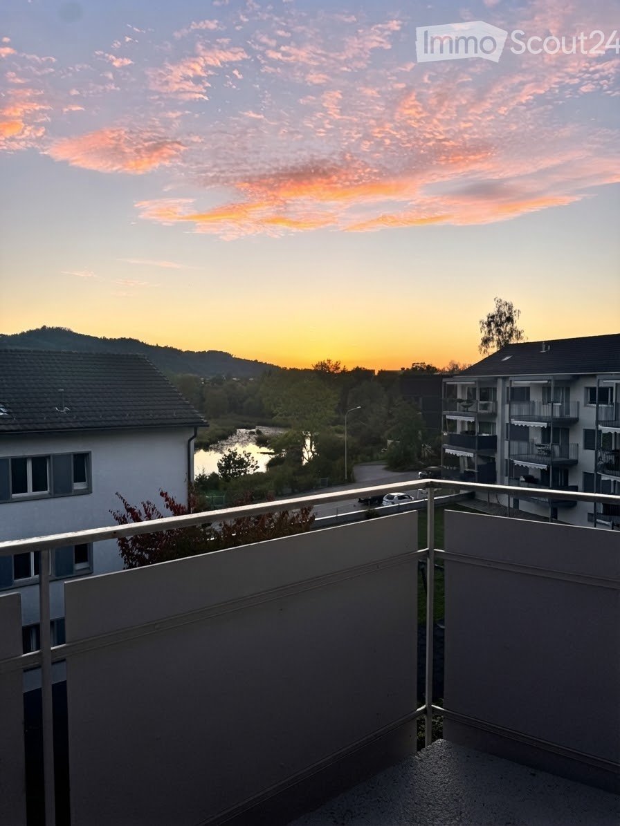 Balcony overlooking a scenic view of a river, surrounding buildings, and a sunset sky.