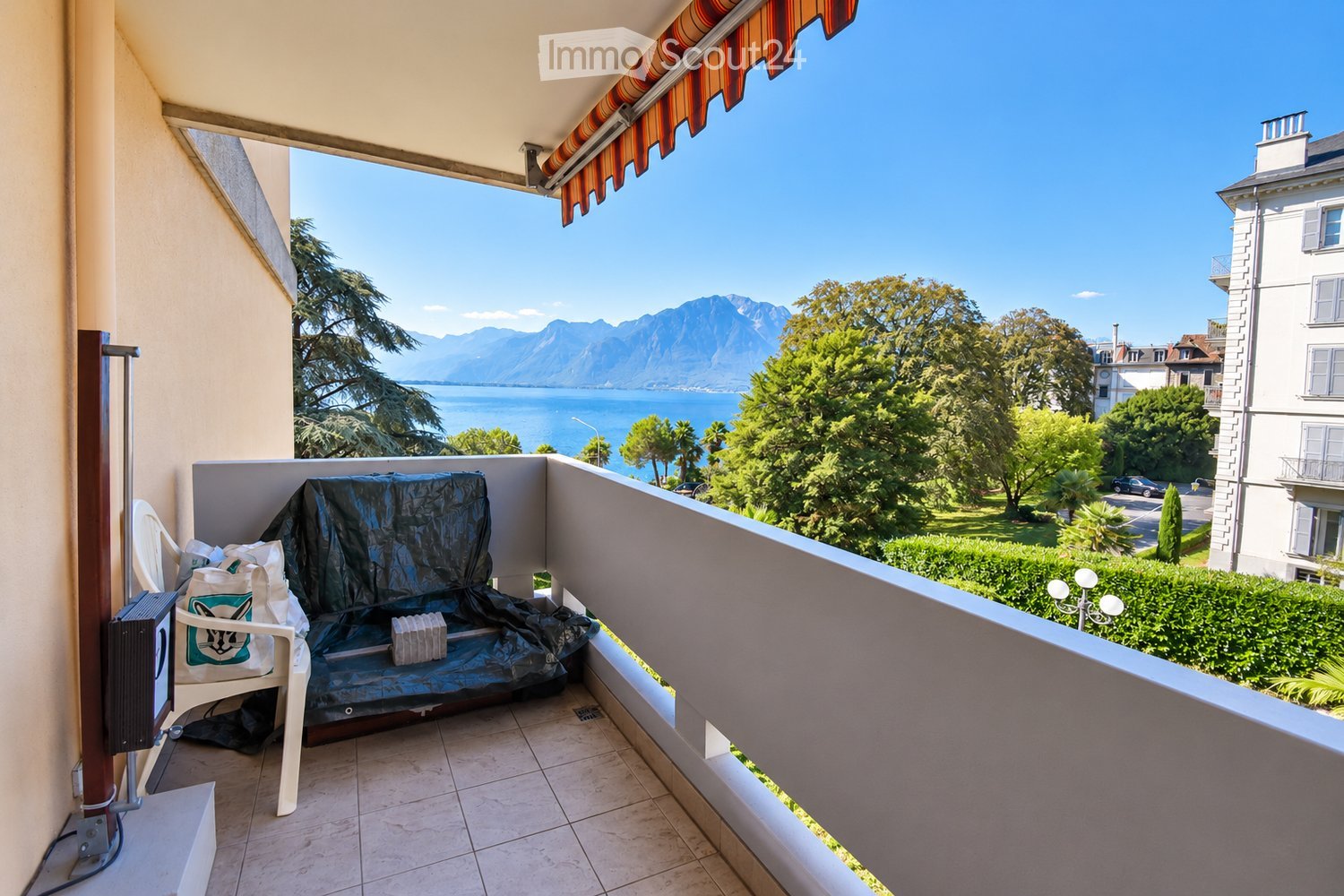 Balcony with tiled floor, covered seating area, and scenic mountain and lake view.