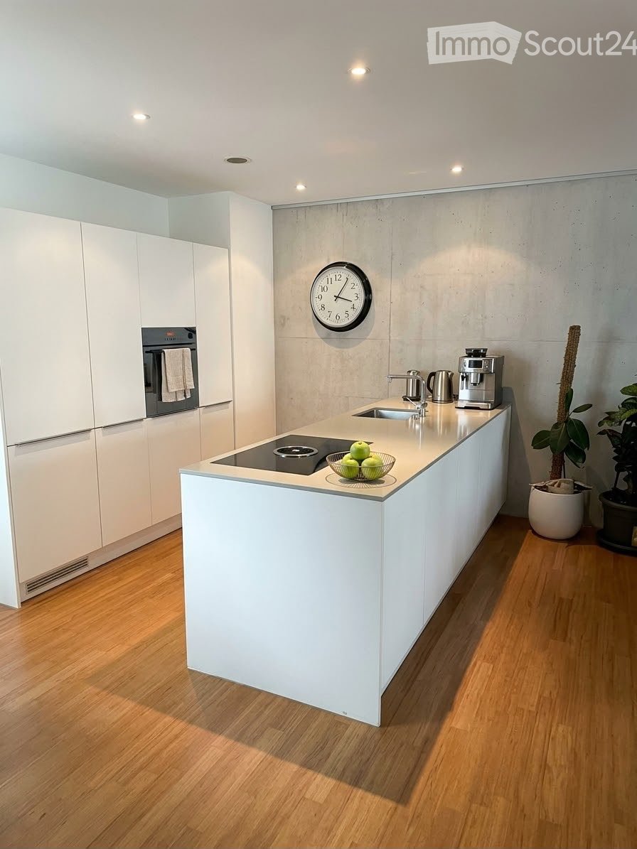 Modern kitchen with white cabinets, induction cooktop, sink, coffee maker, and a clock on the wall.