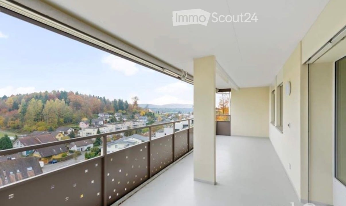 Spacious balcony with white flooring, modern railing, and expansive view of a suburban neighborhood with trees and houses.