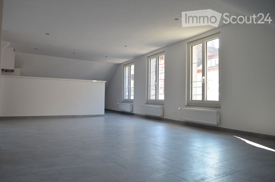 Empty room with light grey walls, large windows, and a smooth tiled floor. No furniture or equipment is present.
