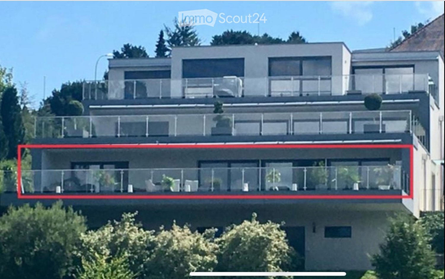 Modern multi-story residential building with large glass balconies and contemporary design.