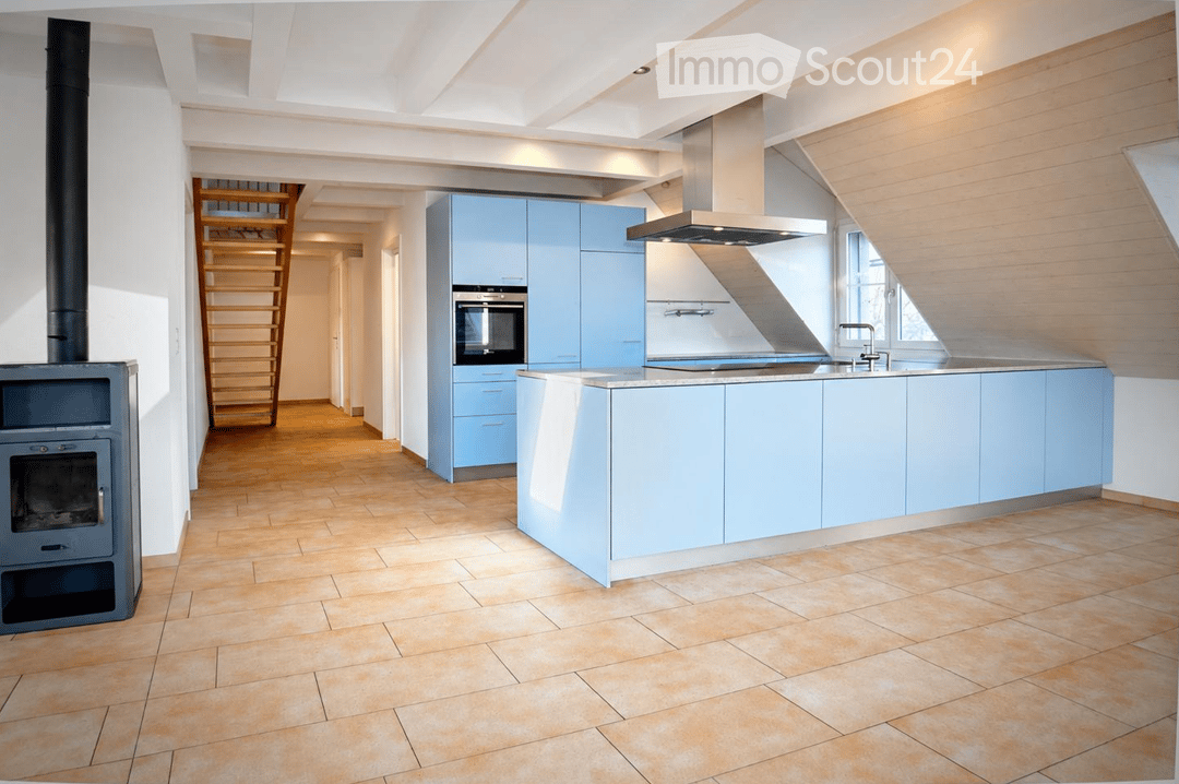 Modern kitchen with light blue cabinets, a central island, a built-in oven, a sink with a faucet, a range hood, and a wooden ladder leading to an upper level.