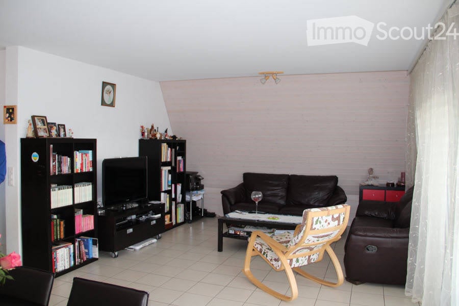 Living room with a dark leather sofa, coffee table, wooden rocking chair, bookshelf, TV, and decorative items.