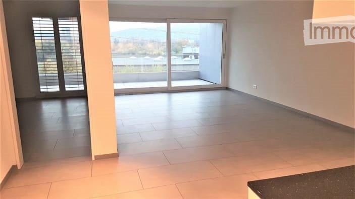 Empty room with large sliding glass doors leading to a balcony, tiled floor, and neutral-colored walls.