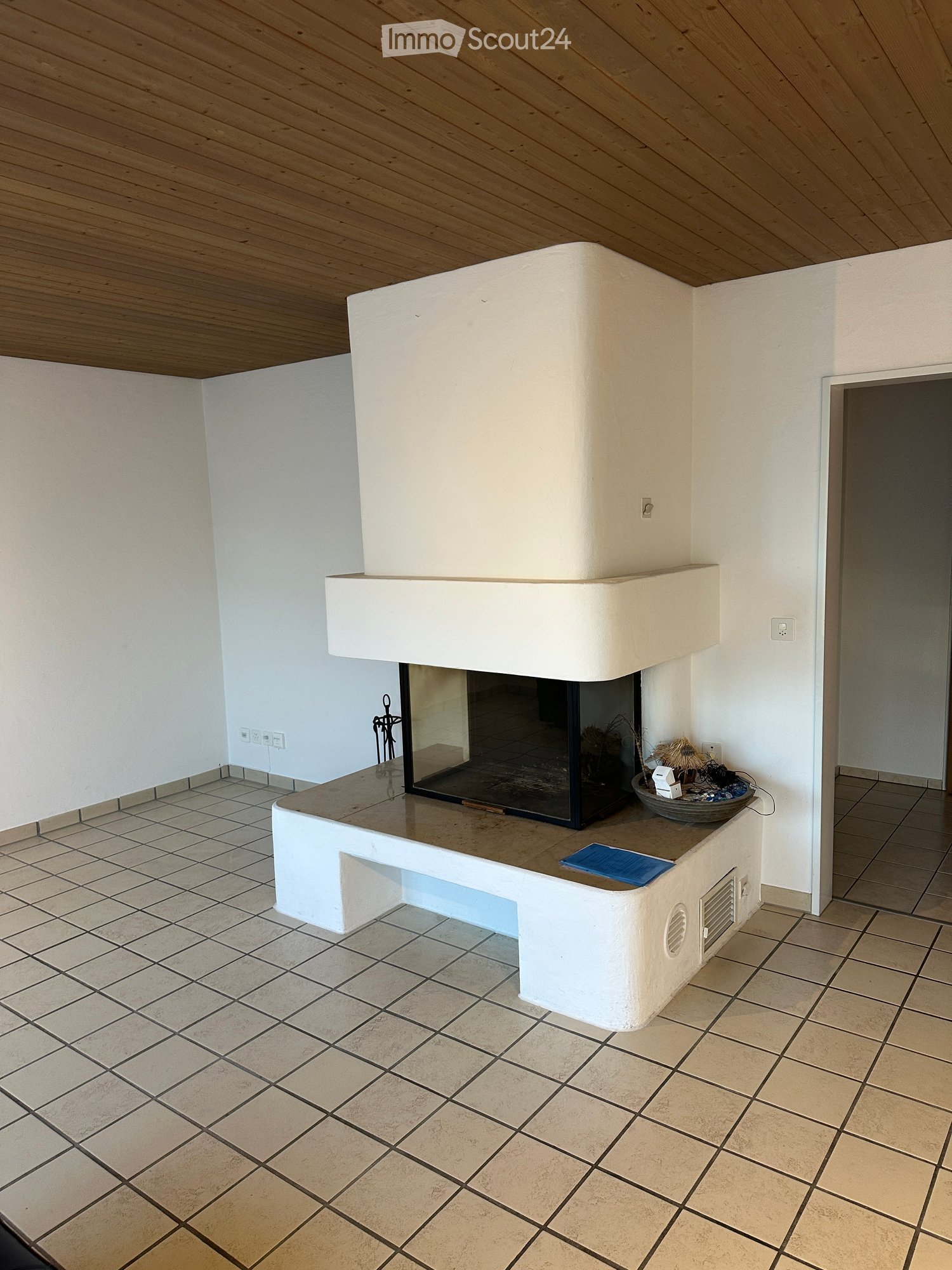 Modern fireplace with white surround, tiled floor, and decorative items on mantel.