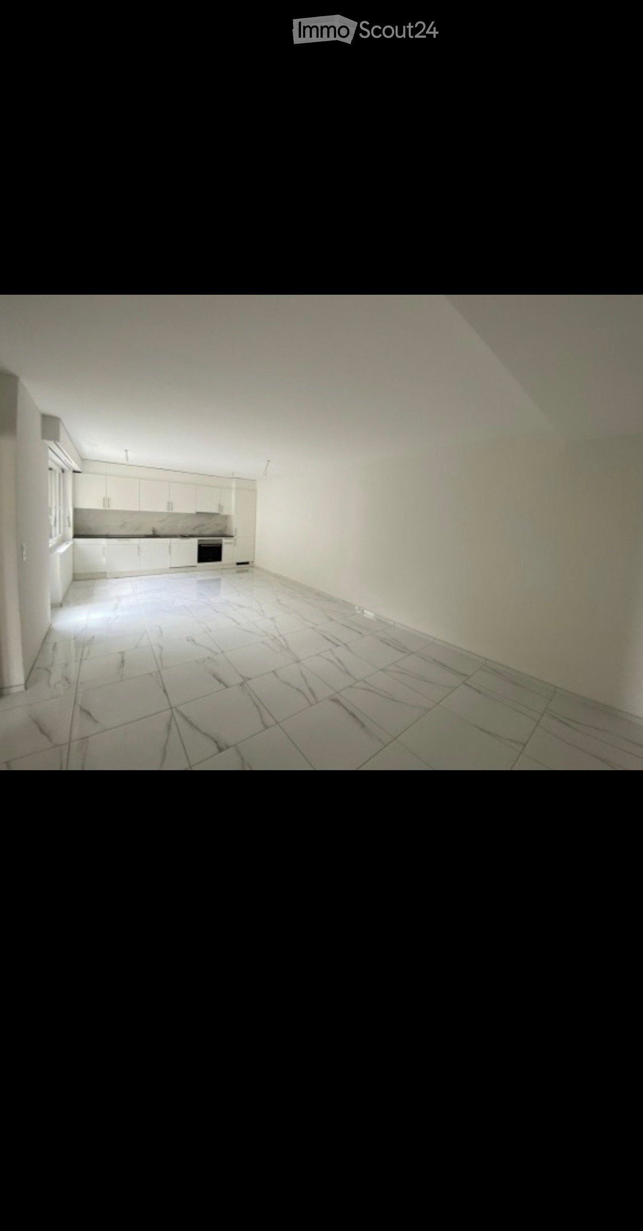Empty kitchen with white cabinets, tiled floor, and basic appliances like a sink and oven, but no furniture or personal items.