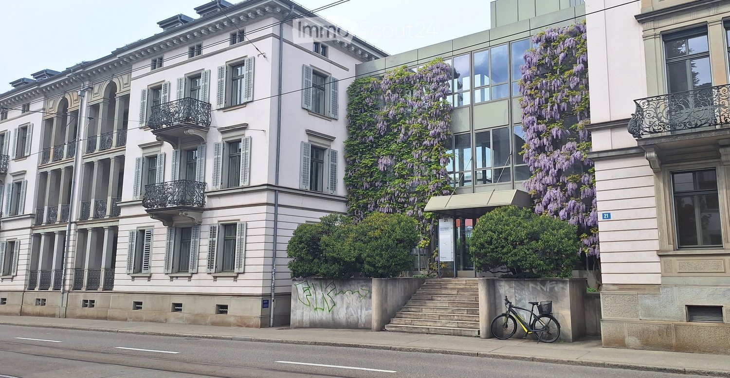 Multi-story residential building with classical architecture, large windows, balconies, and climbing wisteria vines.