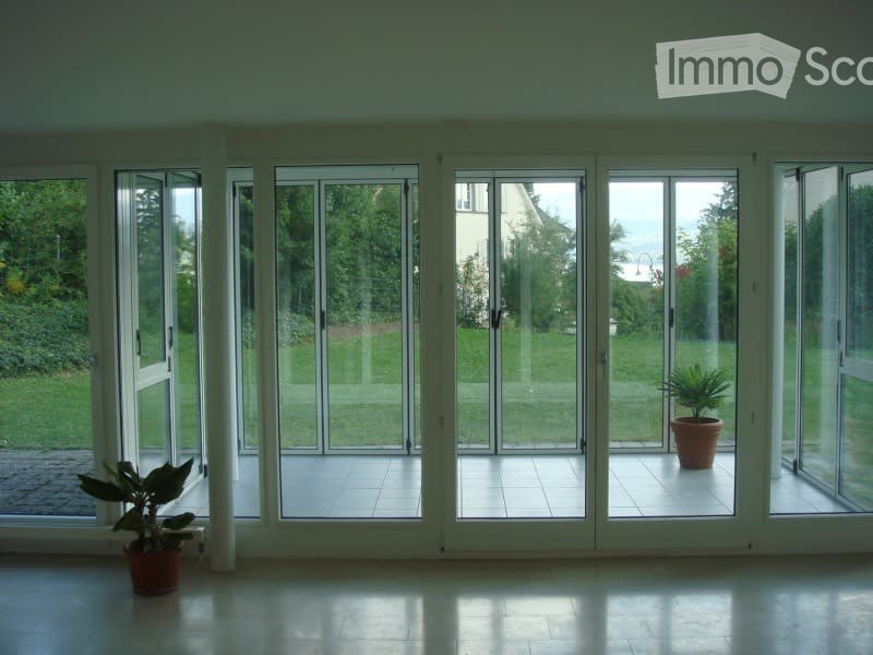 Bright, open room with large glass sliding doors leading to a patio, tiled floor, and two potted plants visible near the doors.