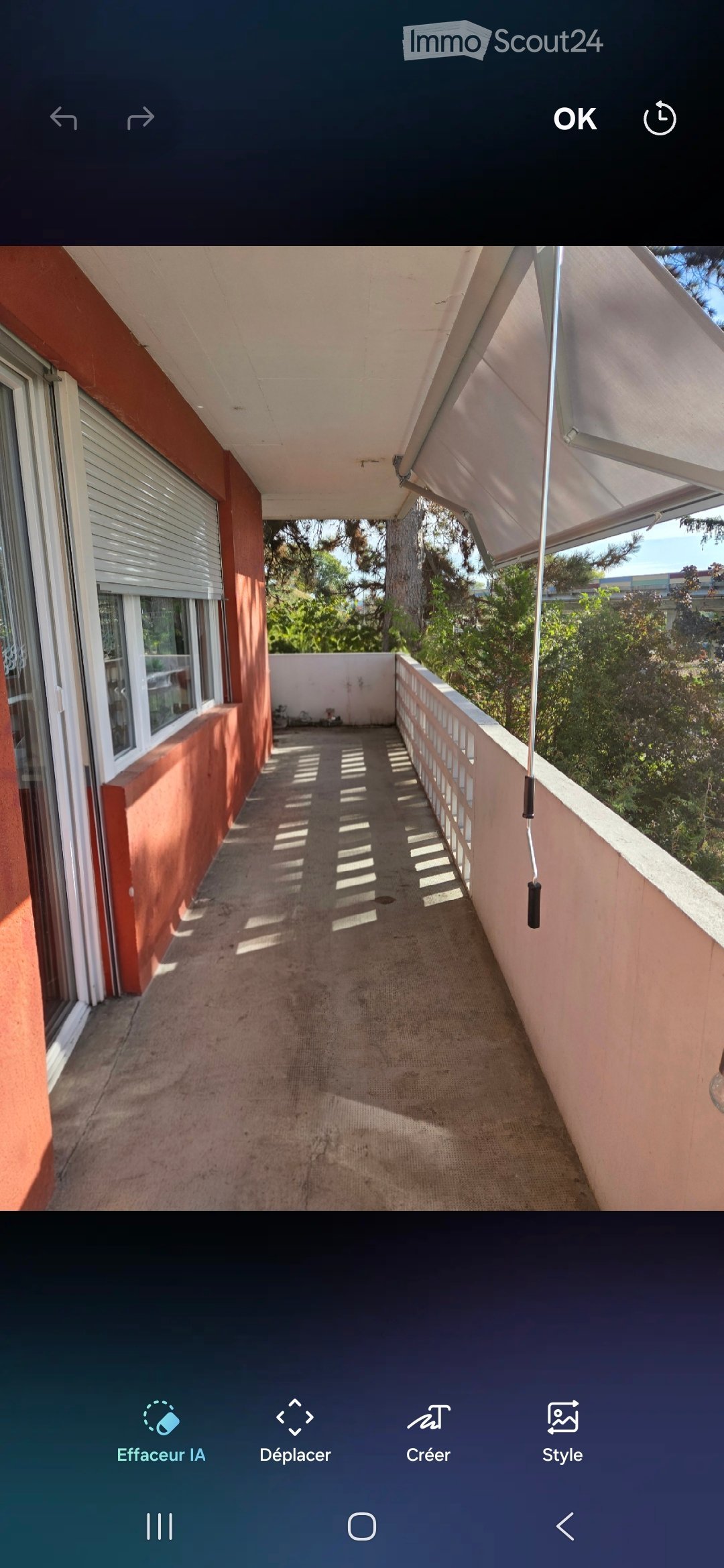 Balcony with beige carpet, white railing, and retractable awning, overlooking greenery.