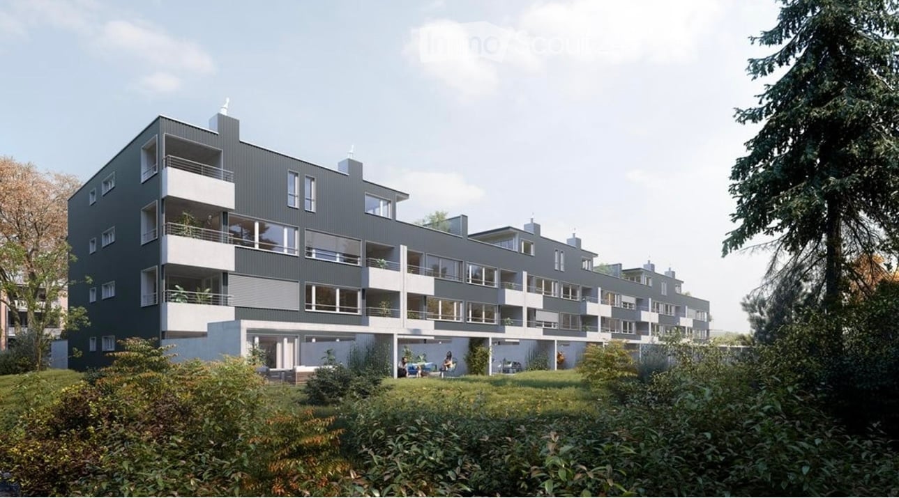 Modern multi-story apartment building with grey and white facade, multiple balconies, and surrounding greenery.