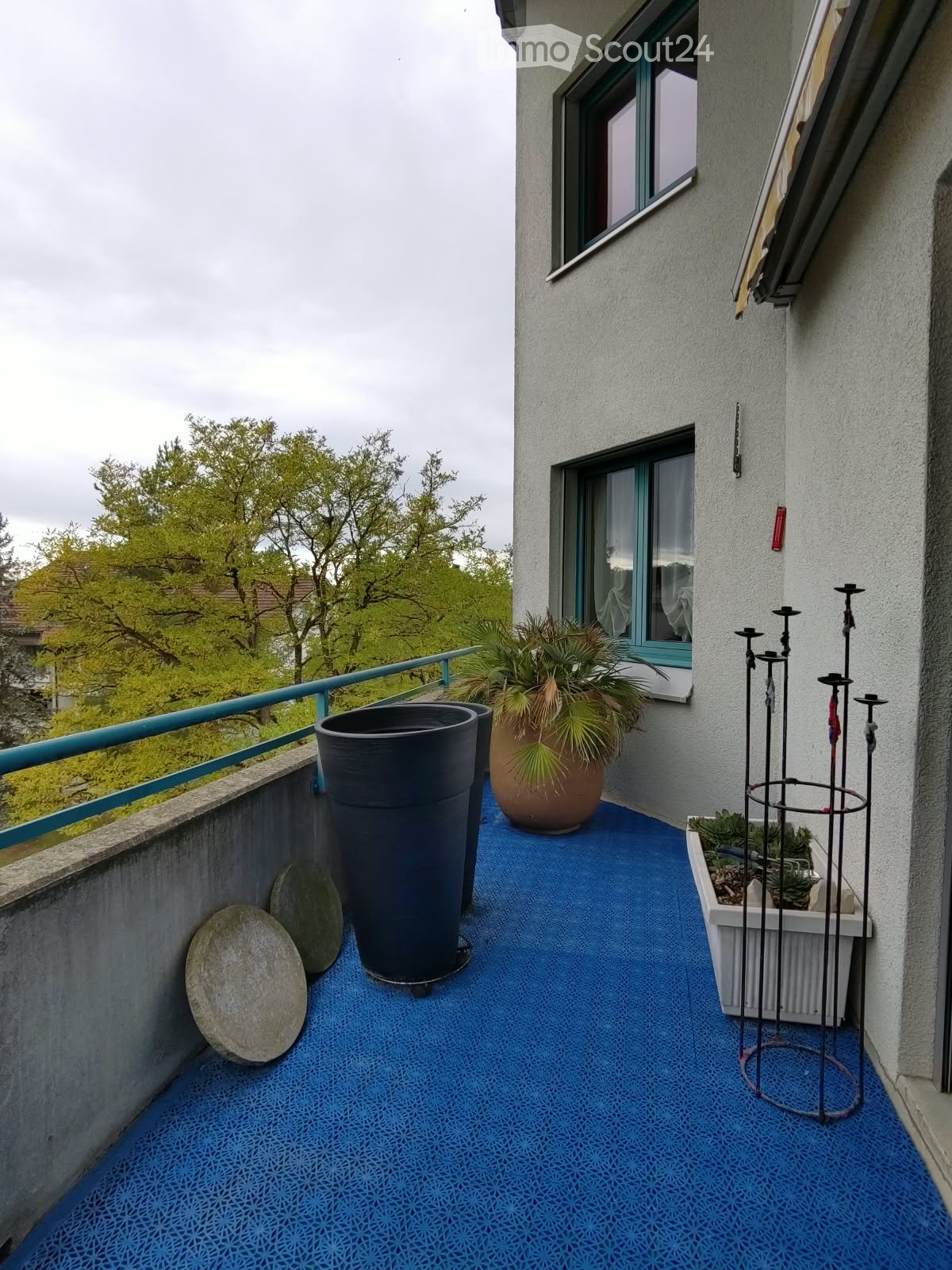 Balcony with blue patterned flooring, potted plants, and candle holders.