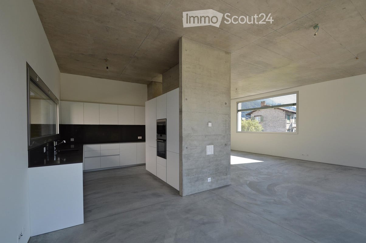 Modern kitchen with white cabinets, stainless steel oven, and a large window overlooking a view.