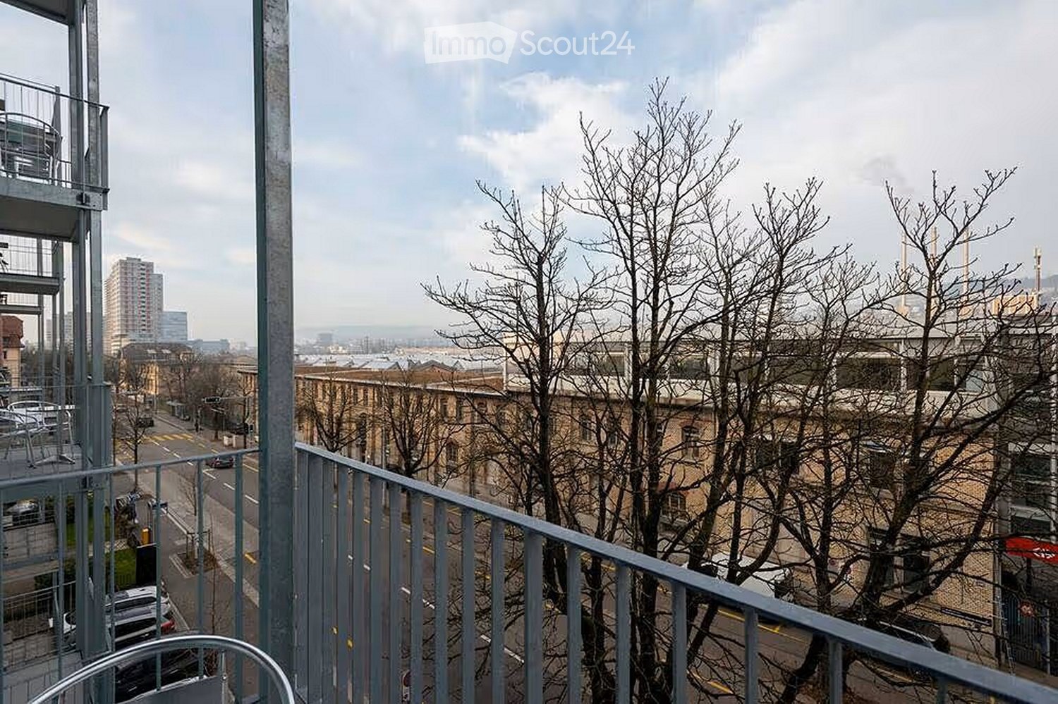 Balcony overlooking a cityscape with bare trees, buildings, and a road below.