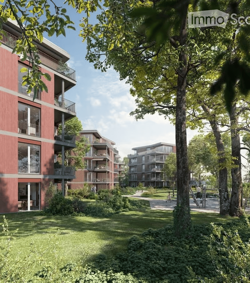 Modern residential complex with red brick facades, multiple balconies, and lush green surroundings.